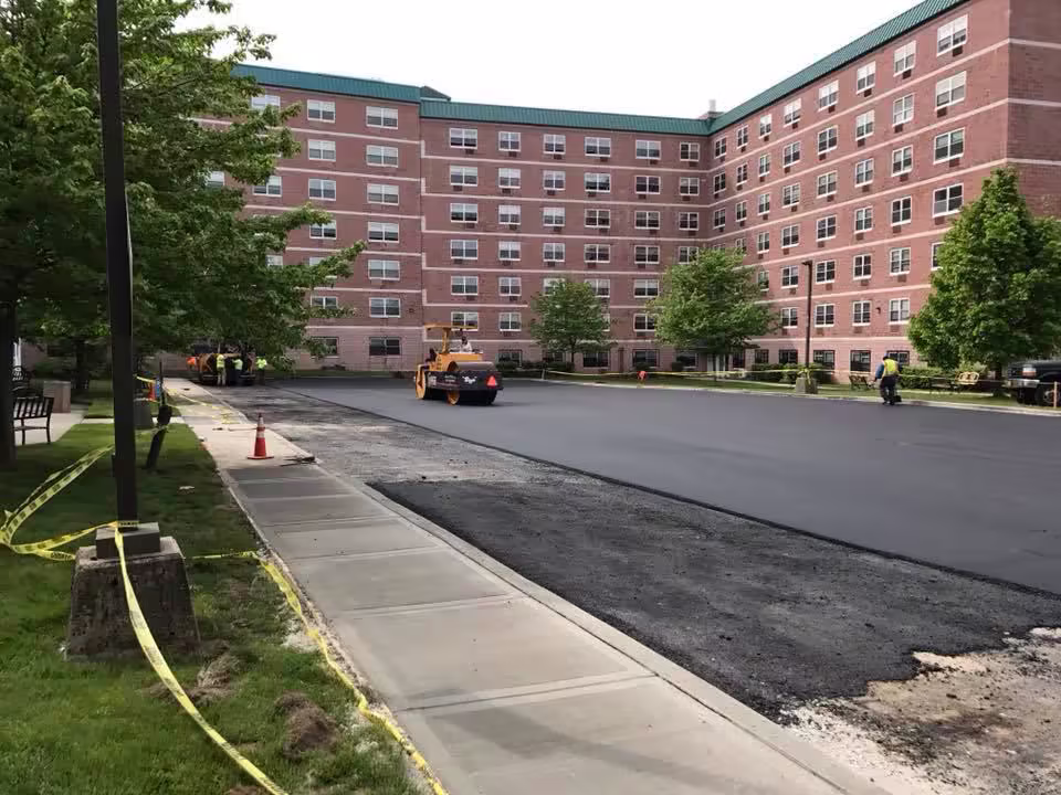 Commercial asphalt paving crew laying fresh blacktop on a parking lot