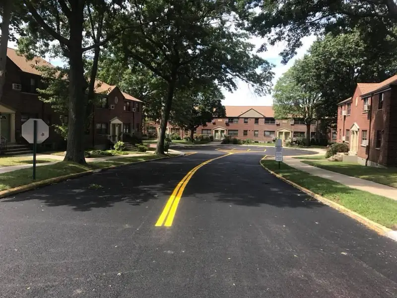 Worker applying black sealcoat to an asphalt driveway